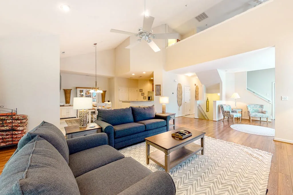 A bright open-plan living room with seating arranged around a coffee table.