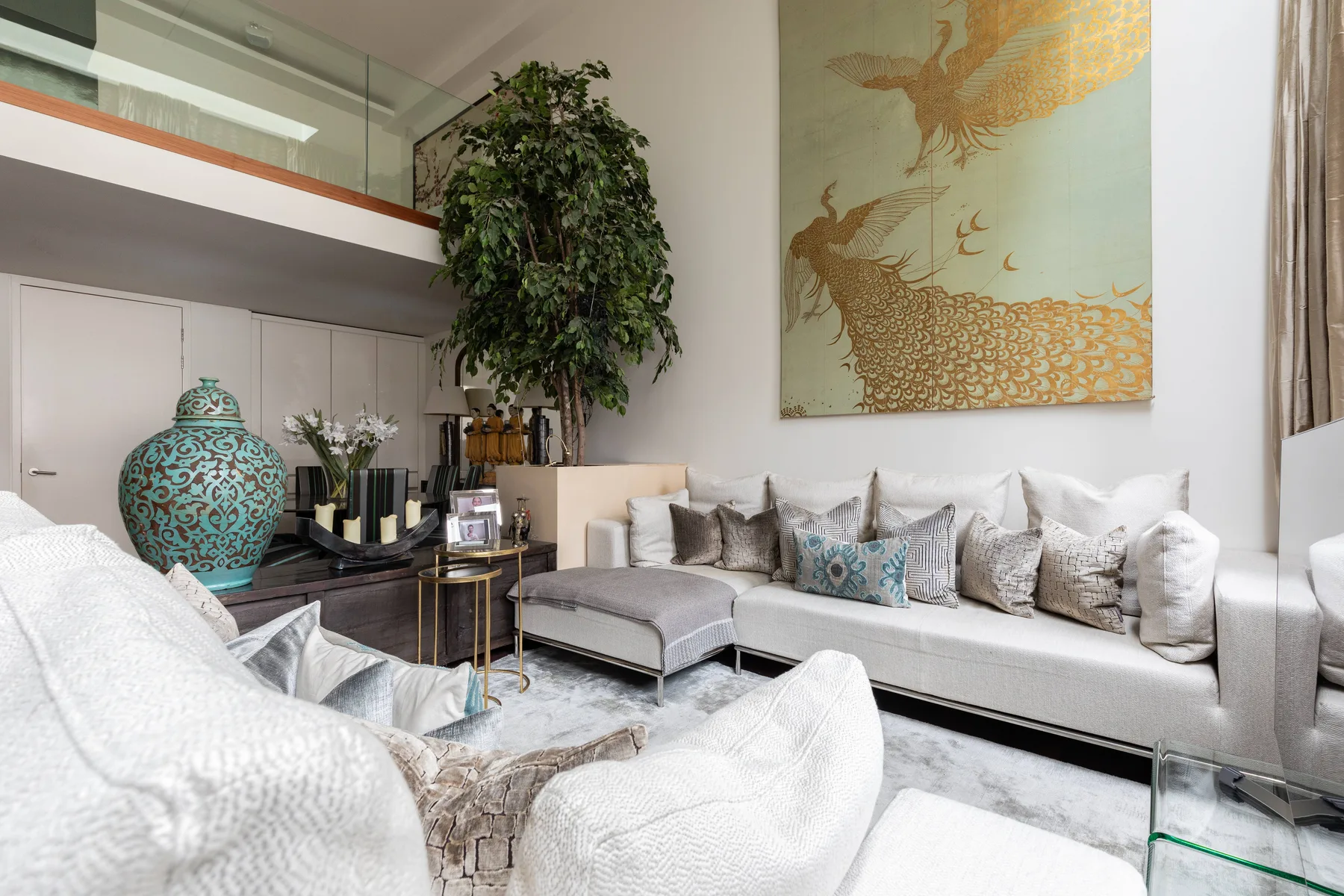 A bright living room with a sectional sofa, patterned cushions, and a large wall artwork.