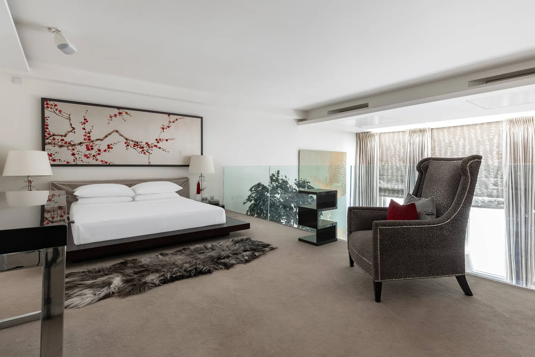 Bedroom with a bed and an upholstered chair beside the window.