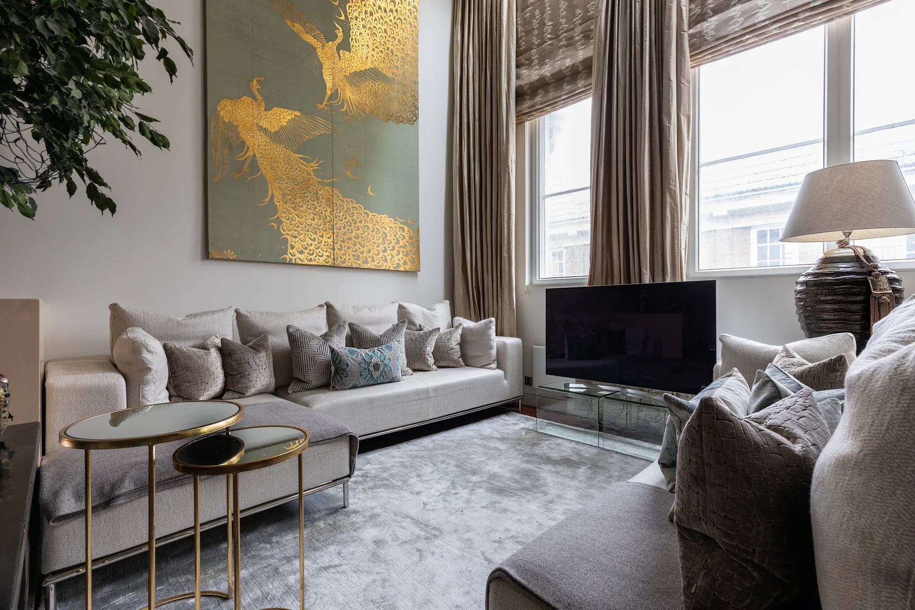 A bright living room with seating, a television, and tall windows.