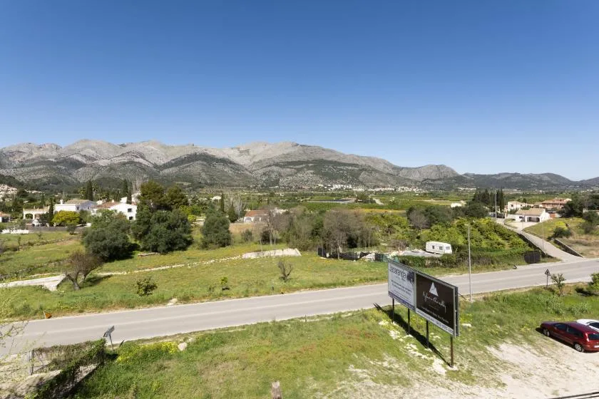 Un paisaje rural con una carretera, campos abiertos y montañas a lo lejos.