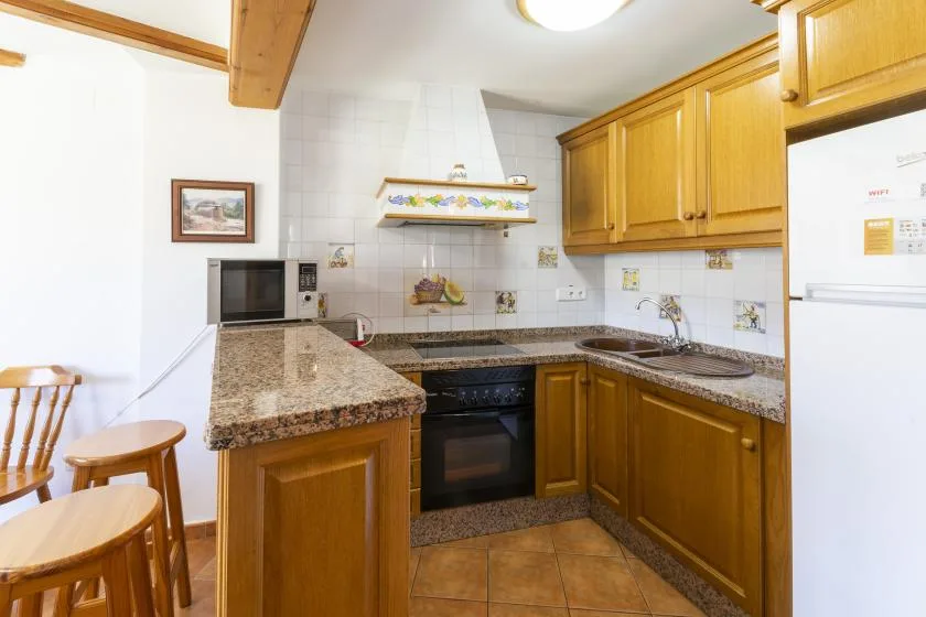 Una cocina con gabinetes de madera, encimeras de granito y horno integrado.