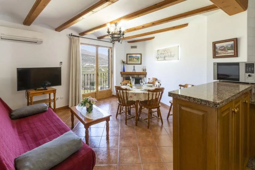 A living and dining area with a table, seating, and glass doors opening to a balcony.