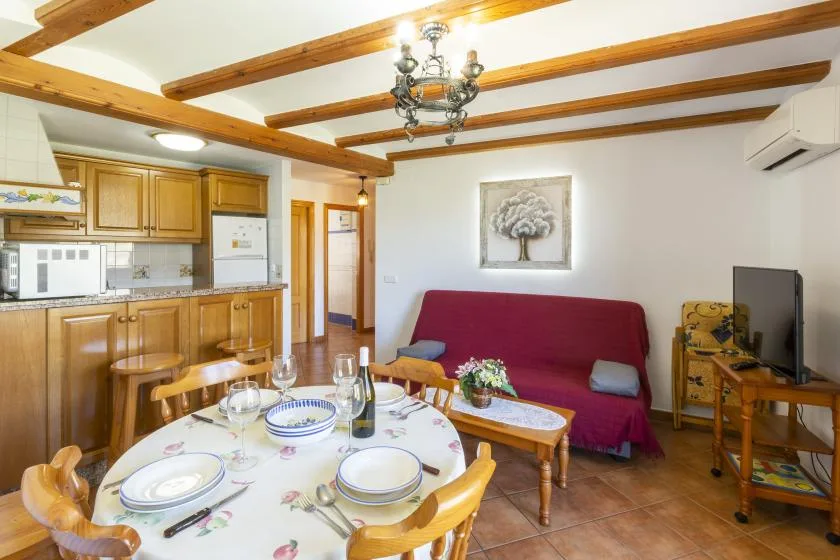 Una zona combinada de cocina y estar con una mesa de comedor y asientos rojos.