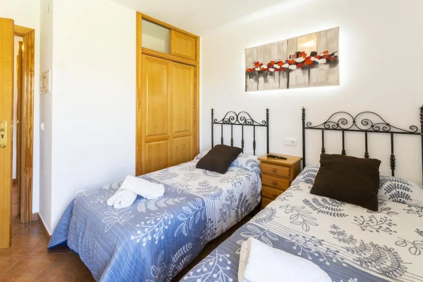 Un dormitorio con dos camas individuales, ropa de cama estampada y un cuadro.