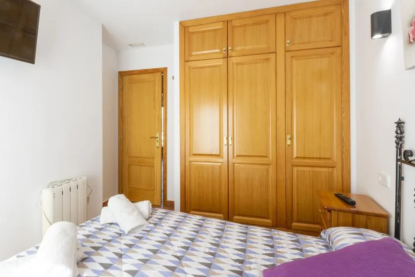Un dormitorio con una colcha estampada y un armario de madera.