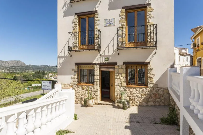 Fachada de un edificio con piedra, balcones y una entrada abierta.