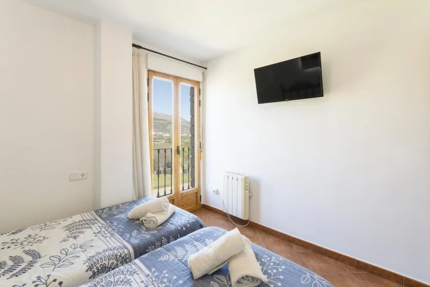 Un dormitorio con dos camas junto a puertas de vidrio que dan a un pequeño balcón.