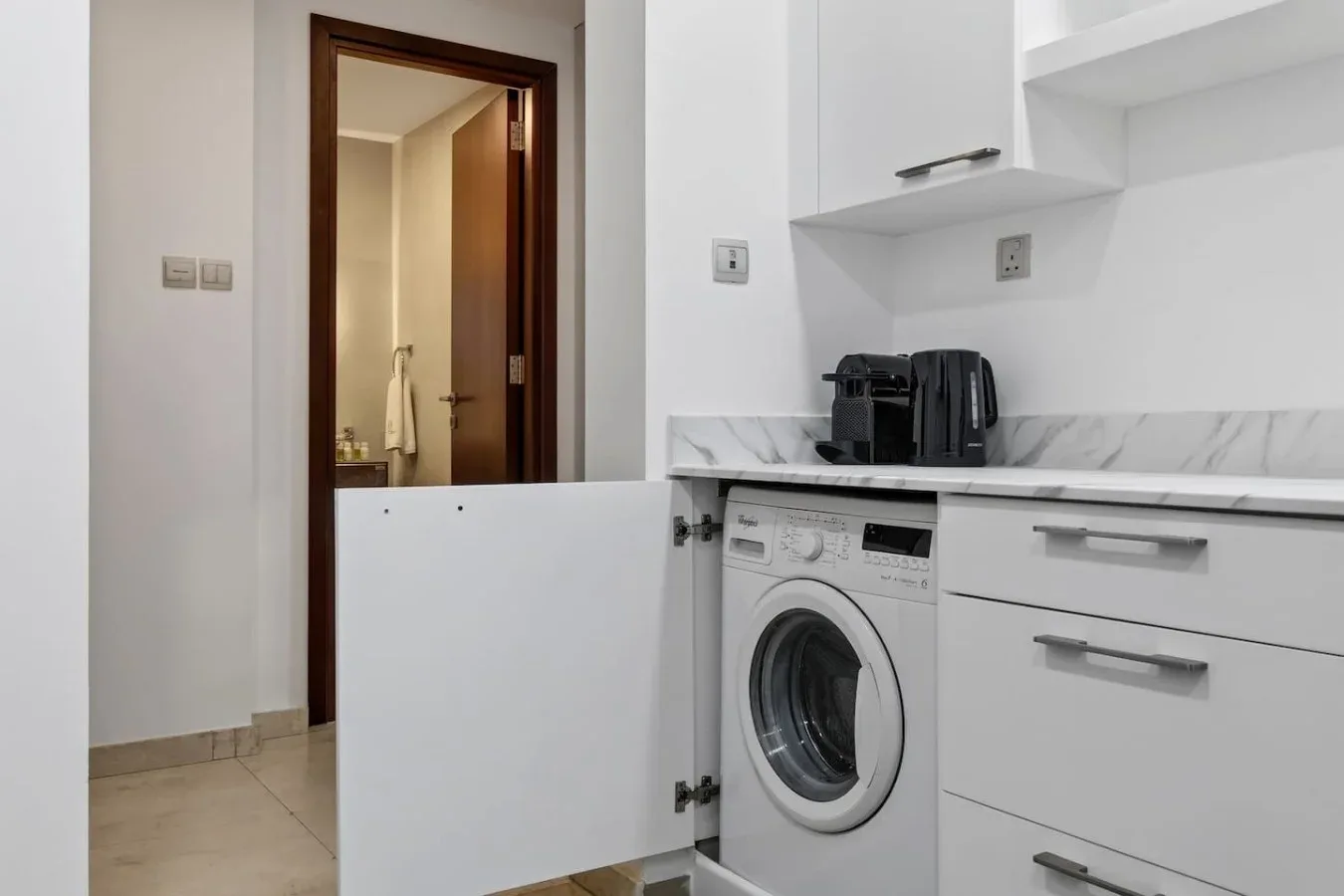 A compact kitchen area with a front-loading washing machine beneath the counter.