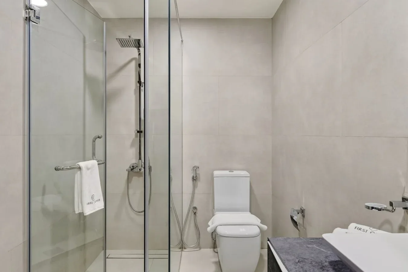 A tiled bathroom with a glass shower and toilet.