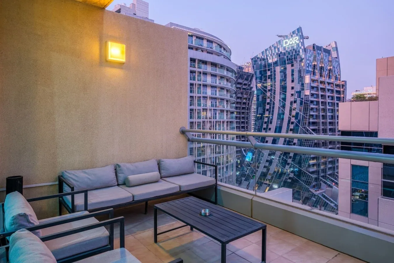 A rooftop terrace with cushioned seating and a view of nearby city buildings.