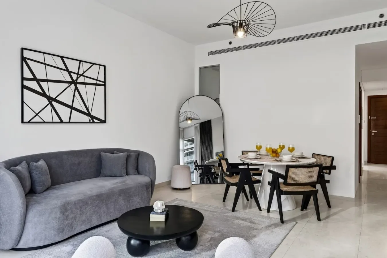 A bright living and dining area with a gray sofa and dining table.