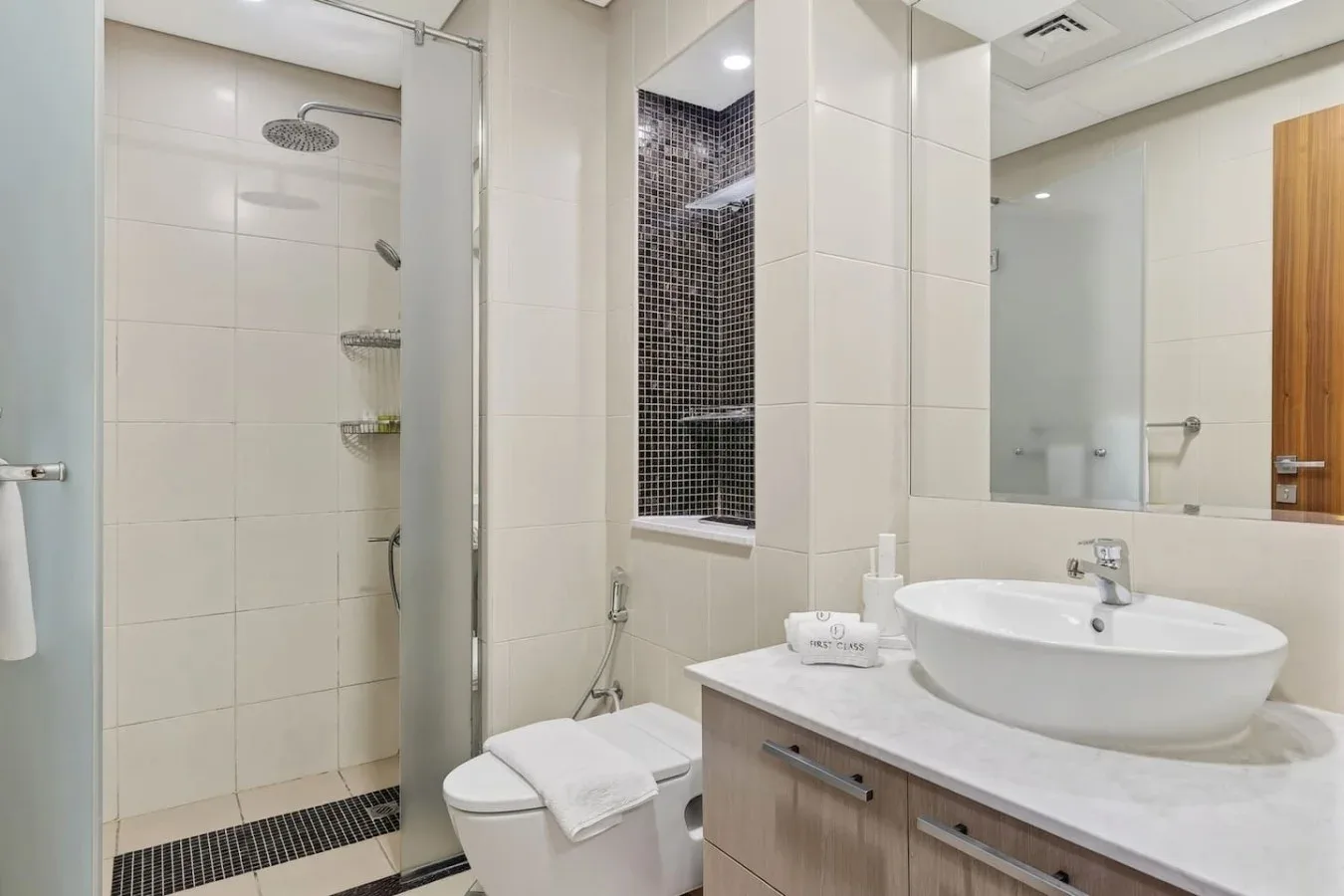A bright tiled bathroom with a shower, toilet, and sink.