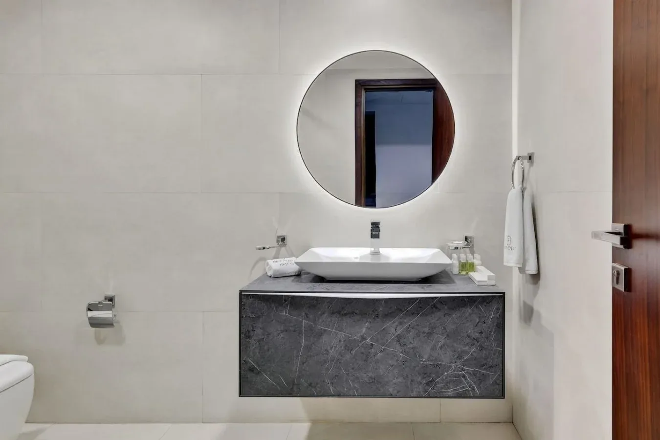 A bathroom vanity with a white sink and round wall mirror.