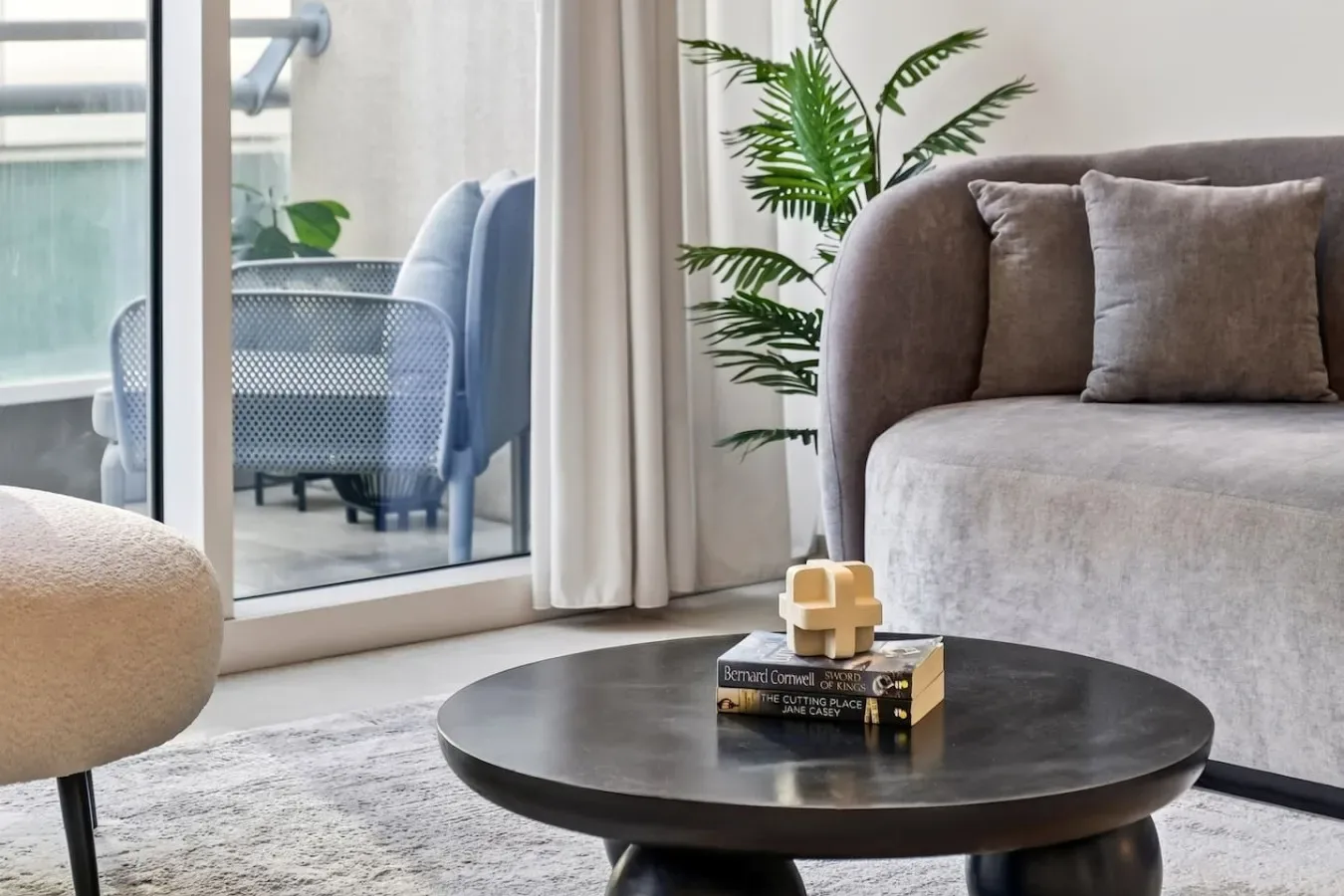 A bright living room with seating beside a large window and a round coffee table.