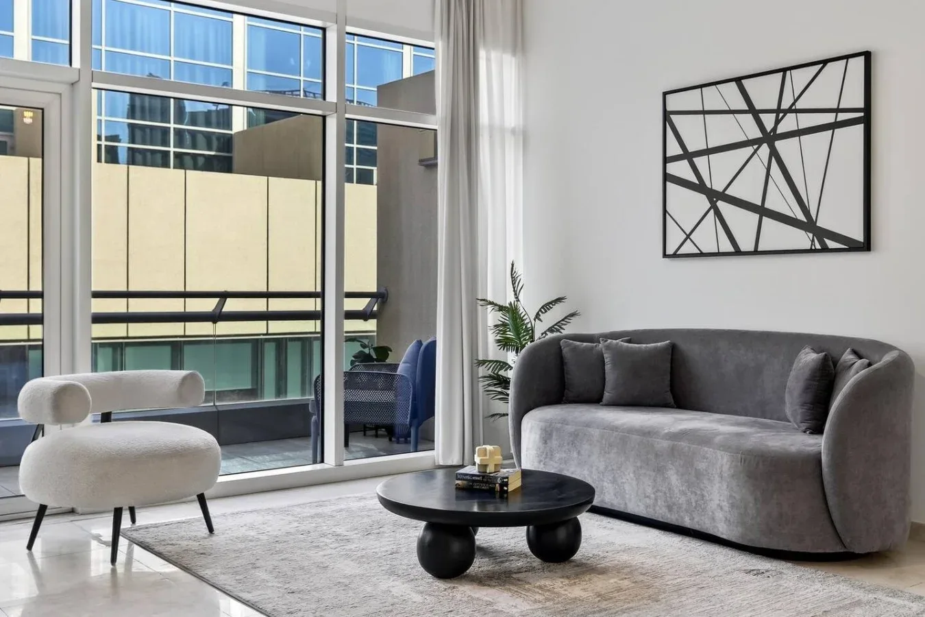 A modern living room with a gray sofa, a round coffee table, and large windows.