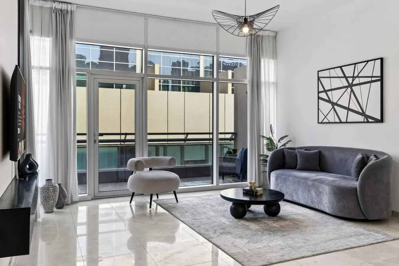 A bright living room with floor-to-ceiling windows, seating, and a coffee table.