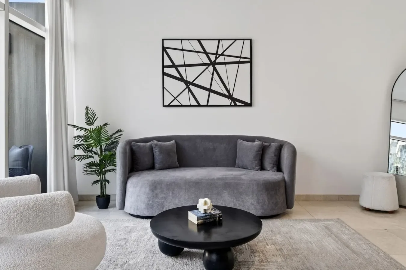 A modern living room with a curved gray sofa, black coffee table, and framed wall art.