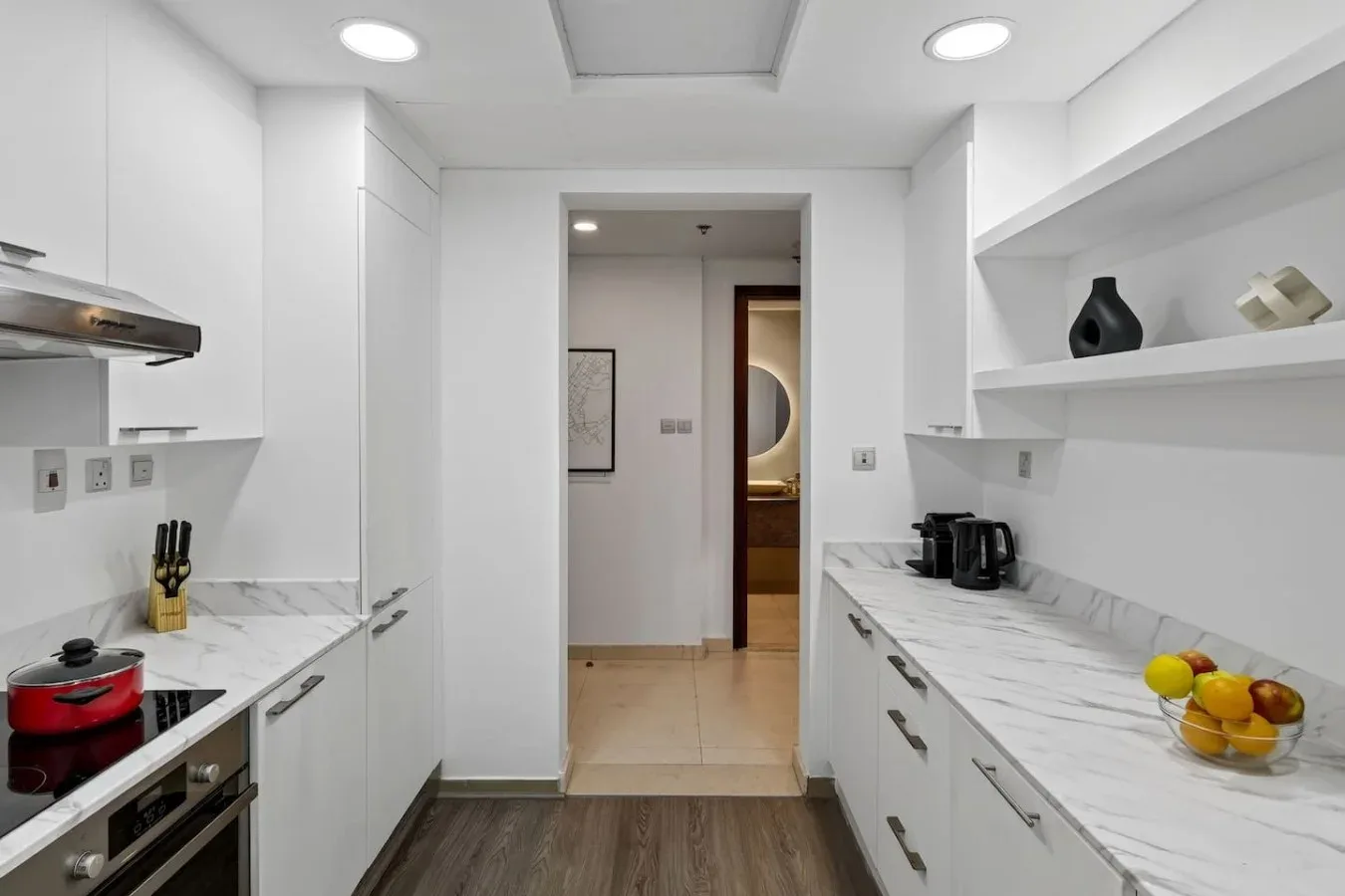 A bright white kitchen with marble-patterned counters and an open doorway.