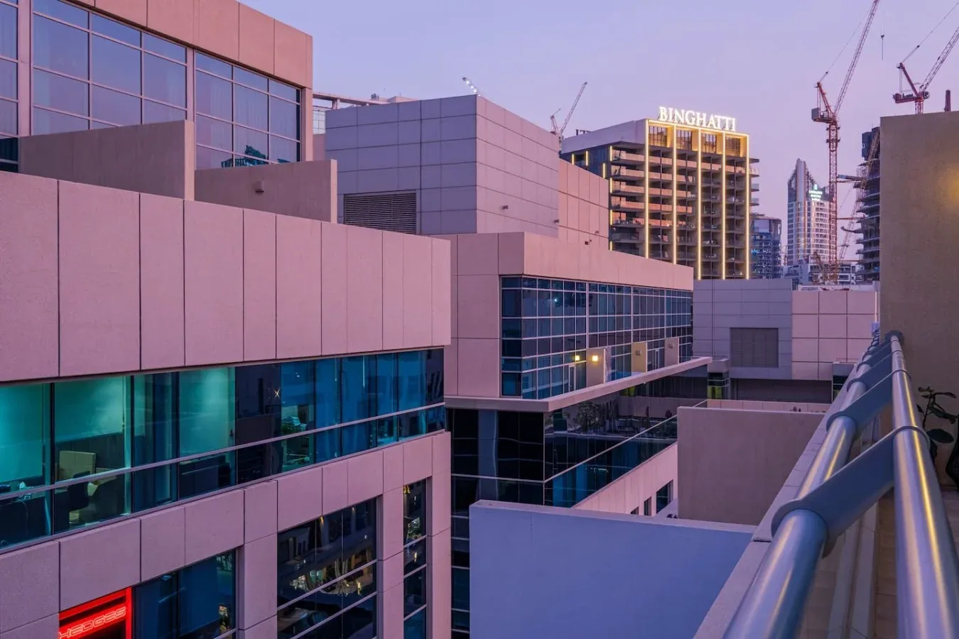An urban building complex with glass windows and a rooftop walkway railing.