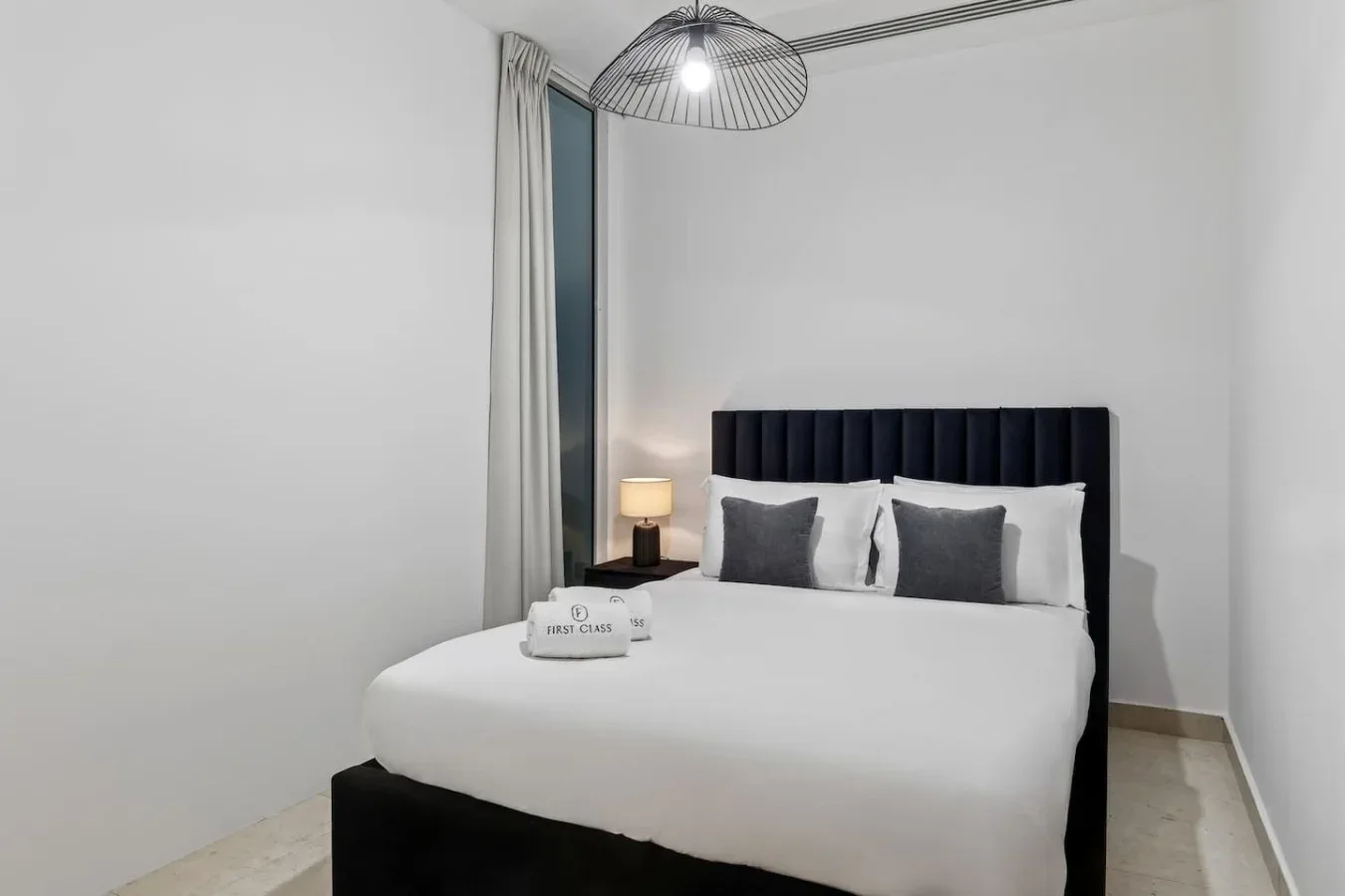 A bedroom with a neatly made bed and gray accent pillows.