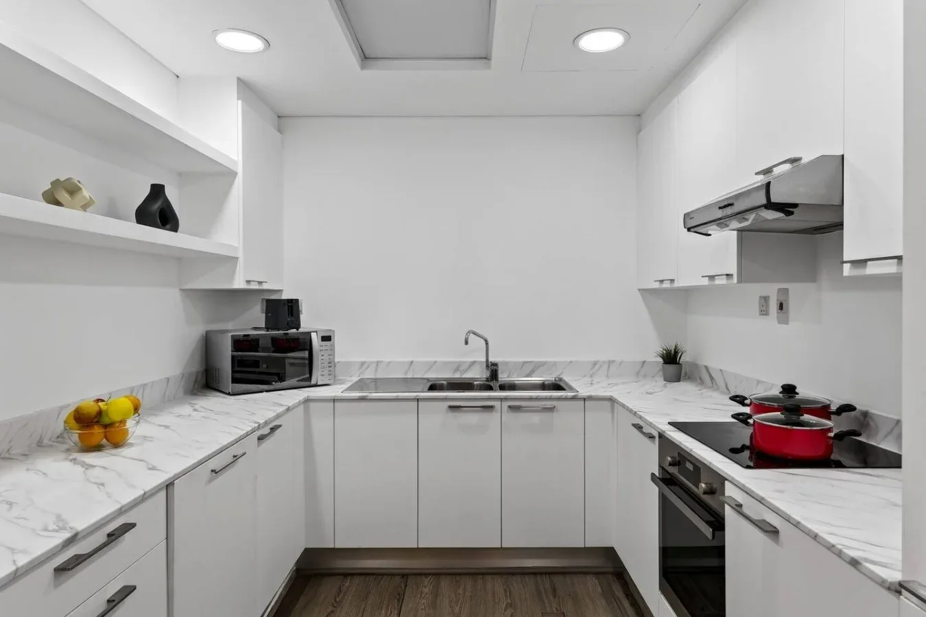 A bright modern kitchen with white cabinetry and marble-patterned countertops.