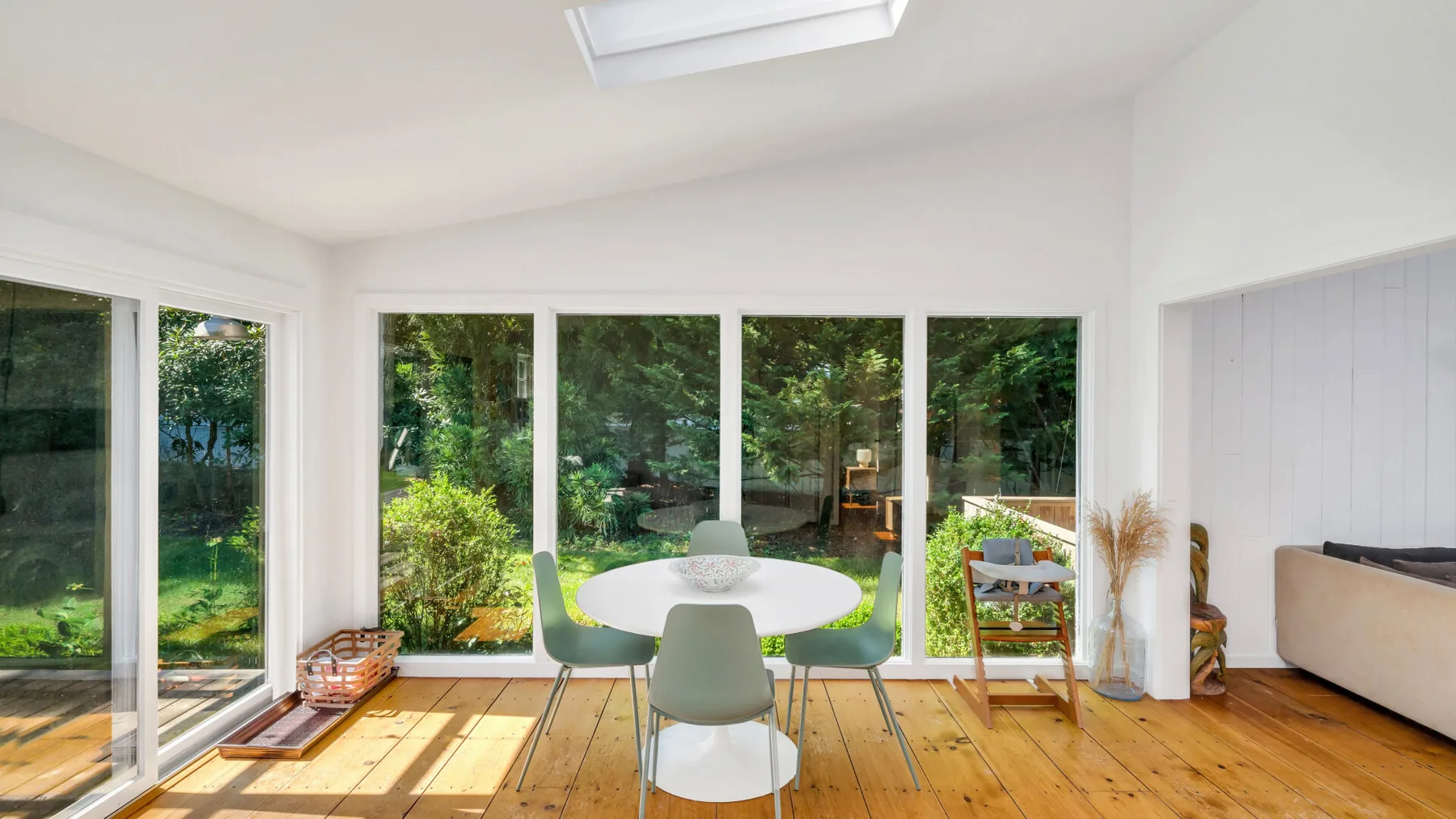 A bright dining area with a table and chairs beside large garden-facing windows.