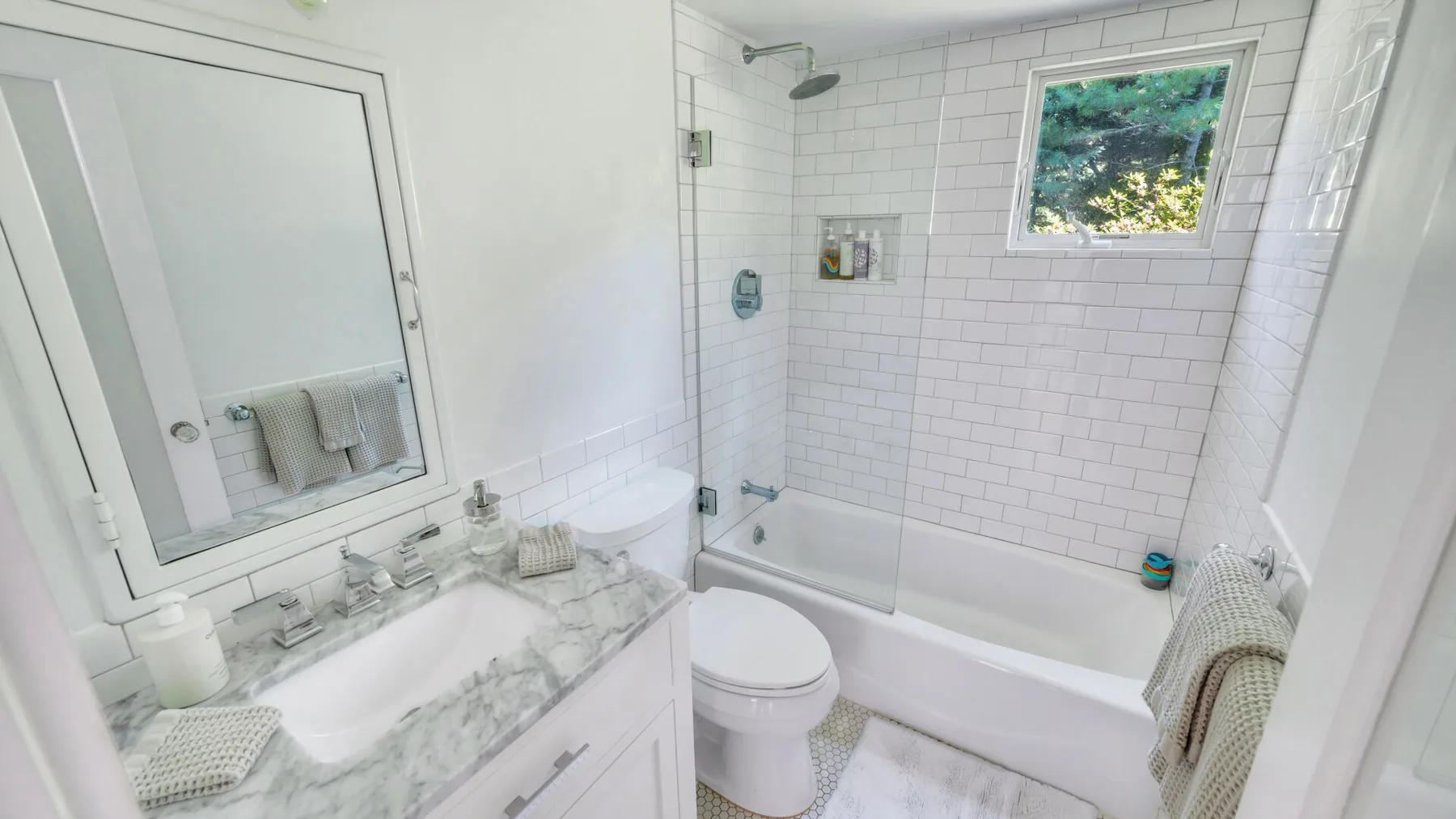 A bright bathroom with a bathtub, shower, and sink.