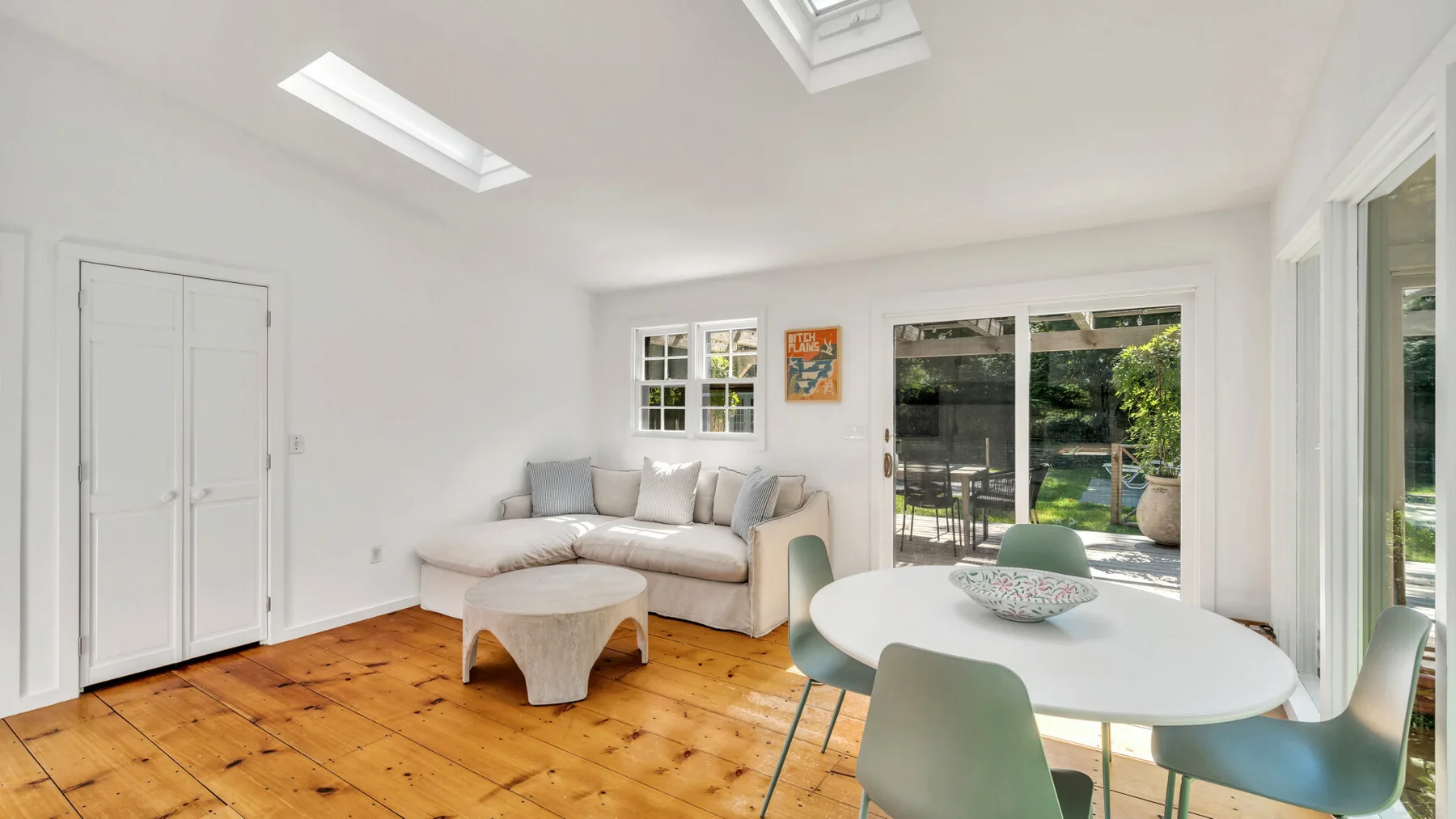 A bright living and dining area with seating, a table, and large windows.