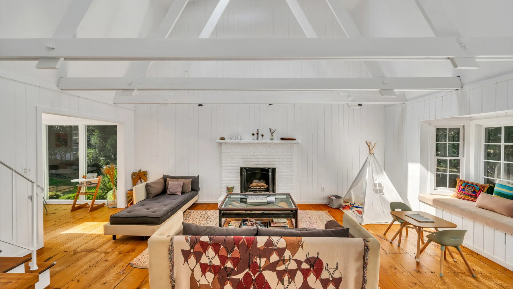 A bright living room with seating around a coffee table and a small teepee.