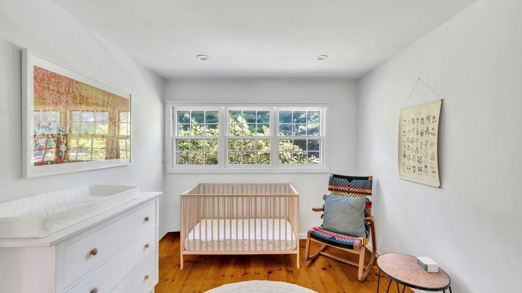 A bright nursery features a wooden crib beside a rocking chair.