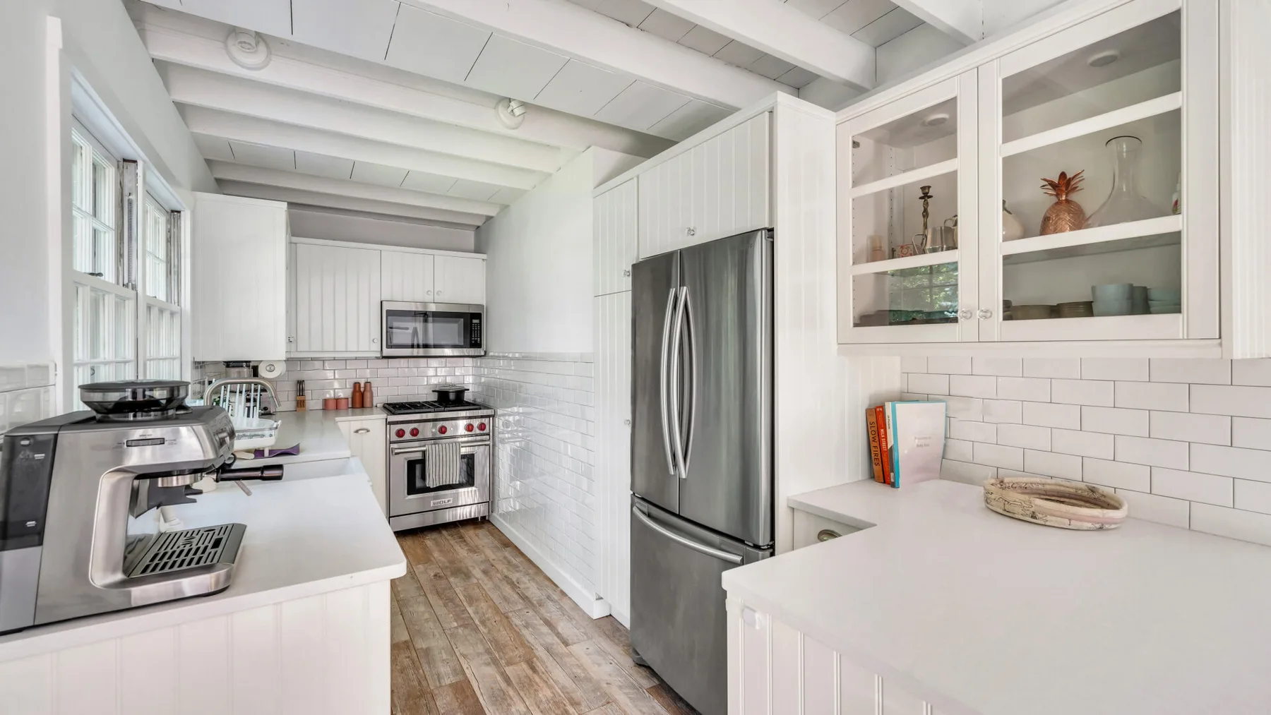 A bright kitchen with white cabinets, stainless steel appliances, and a countertop.