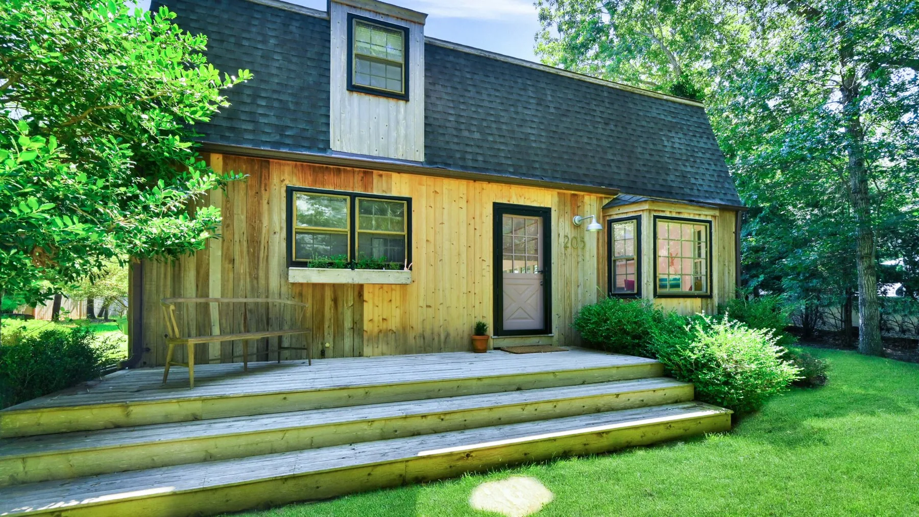 A wooden house with a dark roof and a broad front porch.