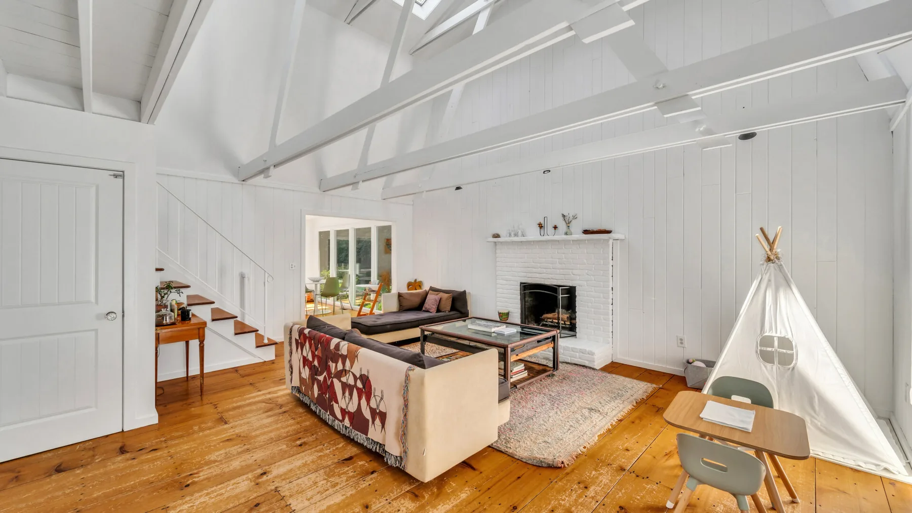 A bright living room with exposed ceiling beams and a seating area.
