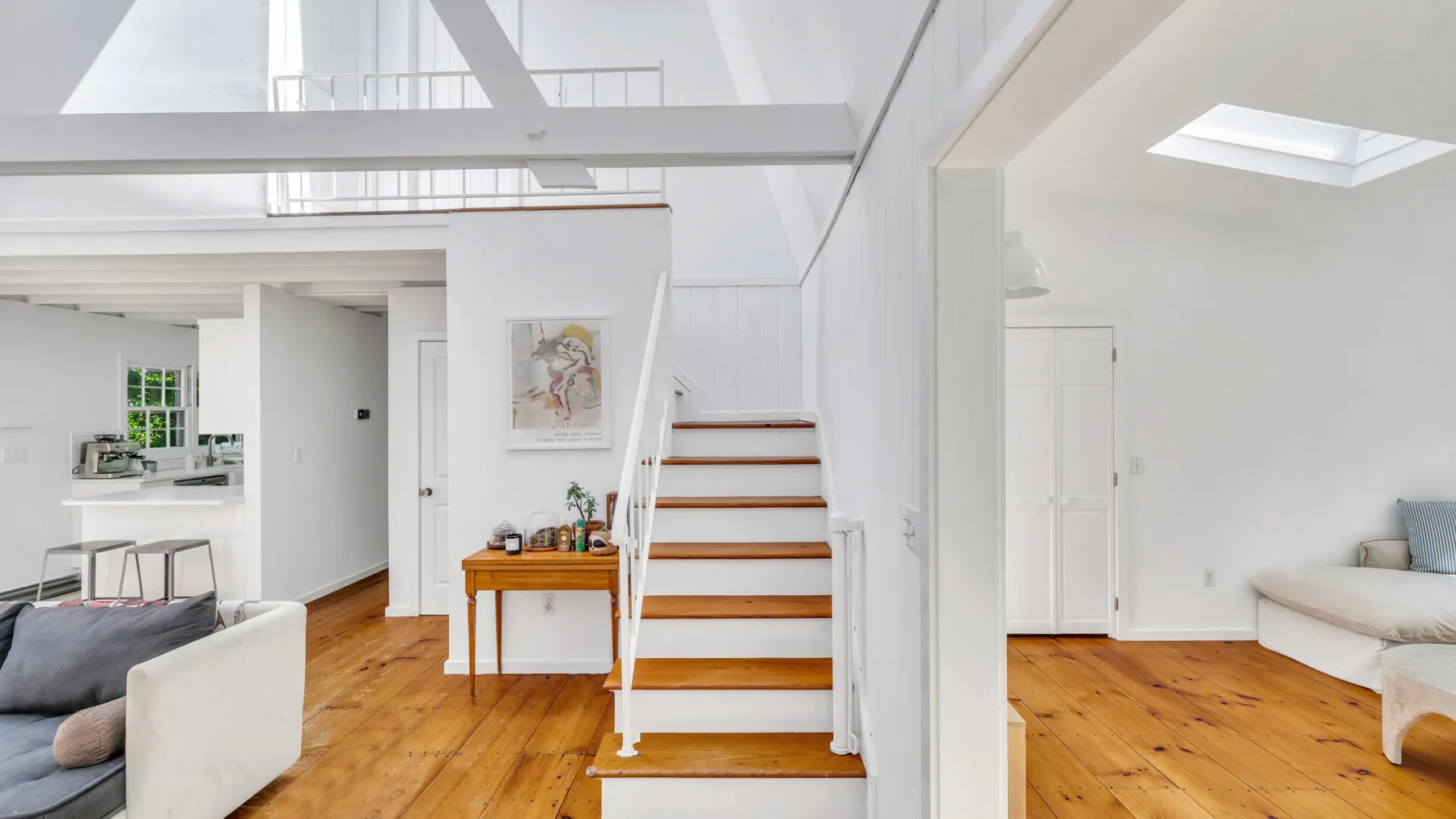 A bright open-plan living area with a wooden staircase and seating.
