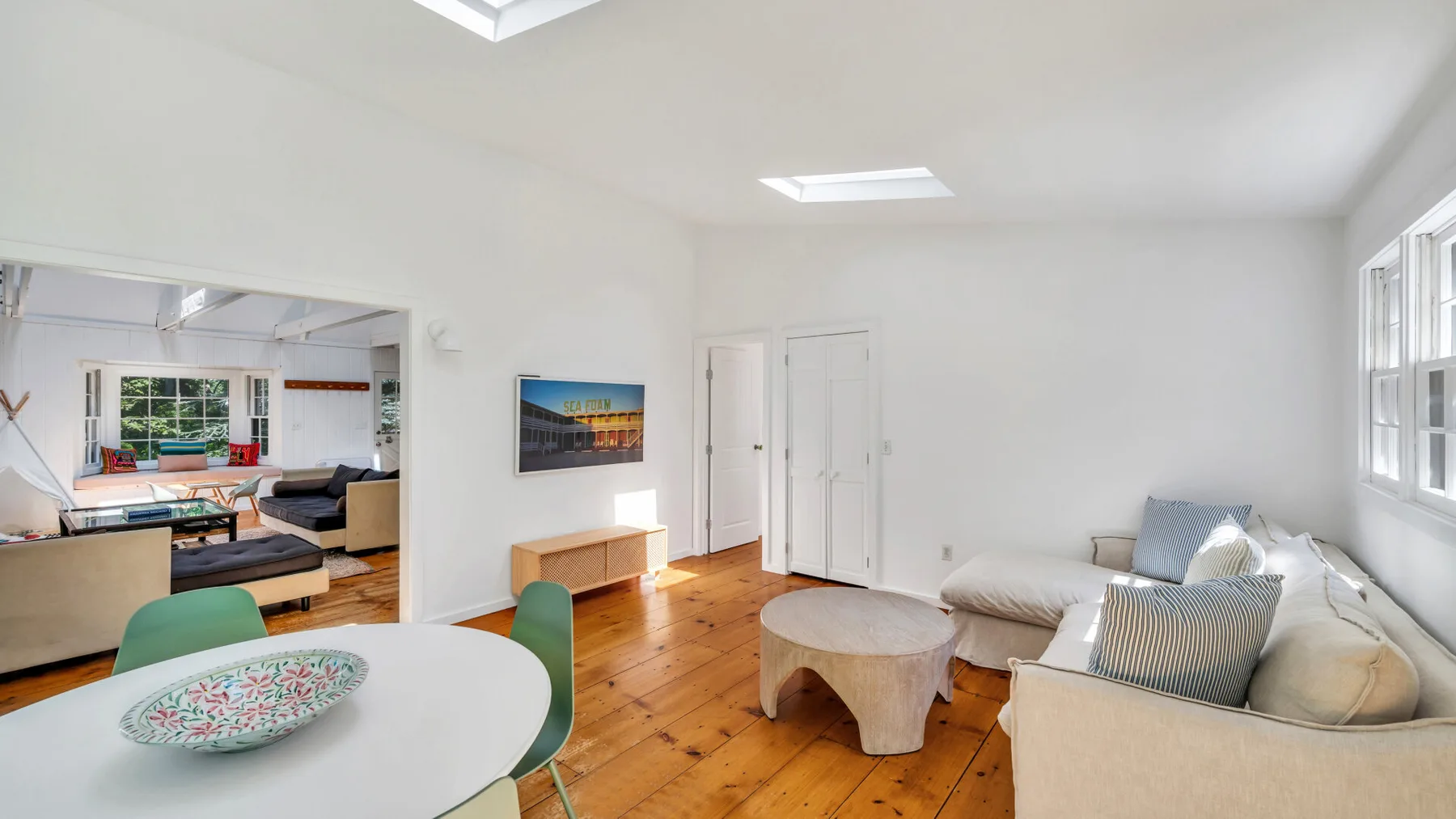 A bright living room with a round table, seating, and wood flooring.