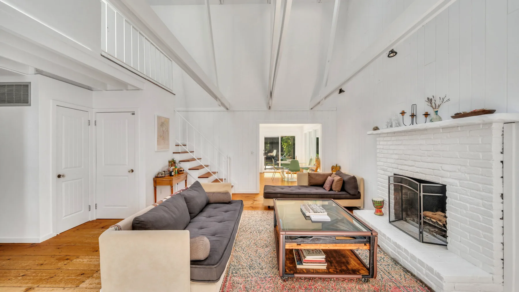 A bright living room with seating, a coffee table, and a white fireplace.