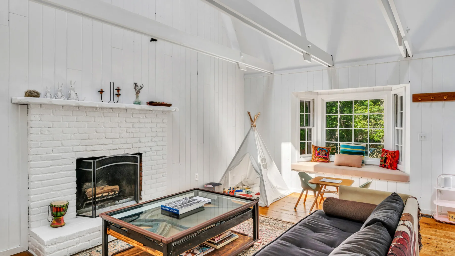 A bright living room with a fireplace, a sofa, and a window seat.