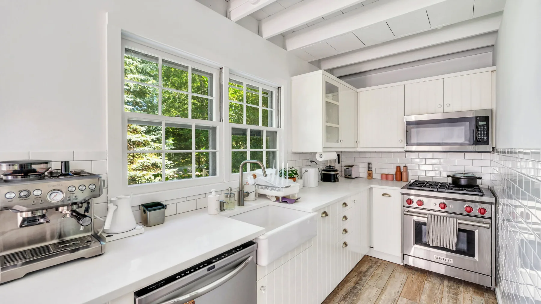 A bright kitchen with white cabinets, a sink, and large windows.