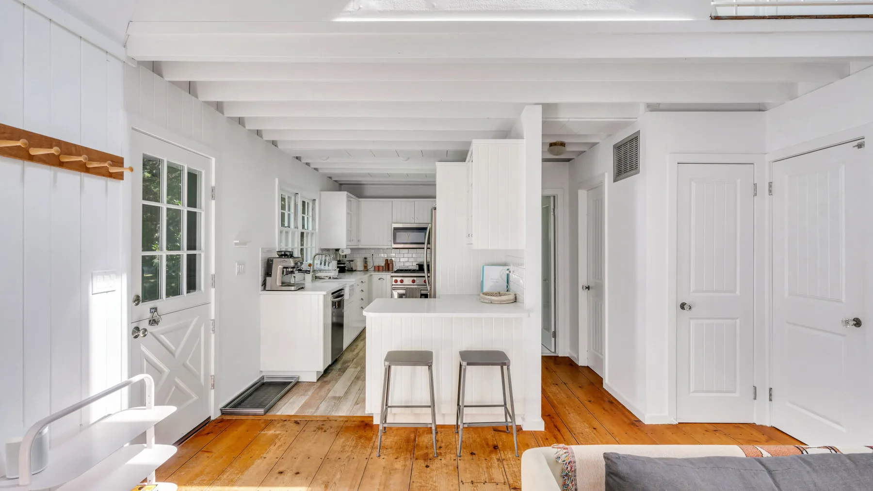 A bright kitchen with a white island and two stools.