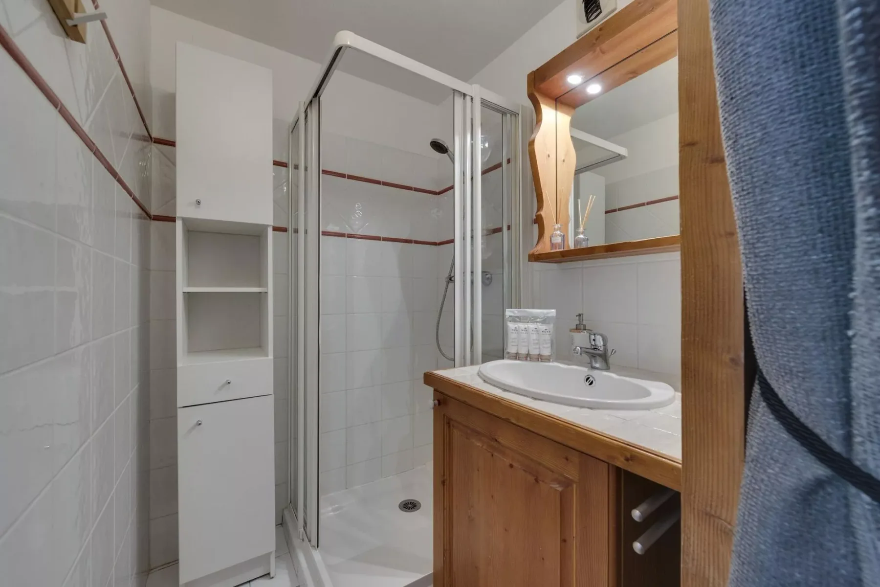 A bathroom with a glass shower and a wooden vanity with a sink.