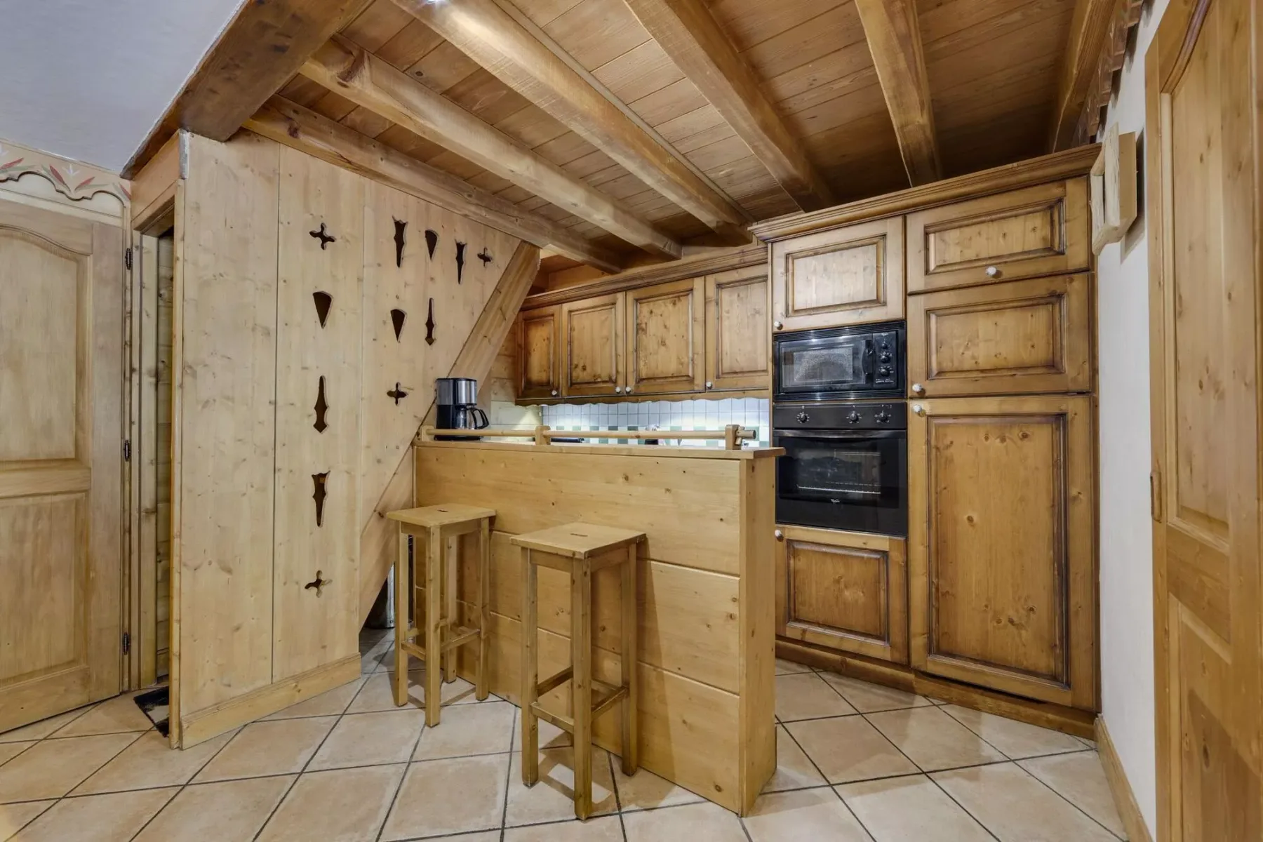 A compact wooden kitchen with a breakfast counter and built-in oven.