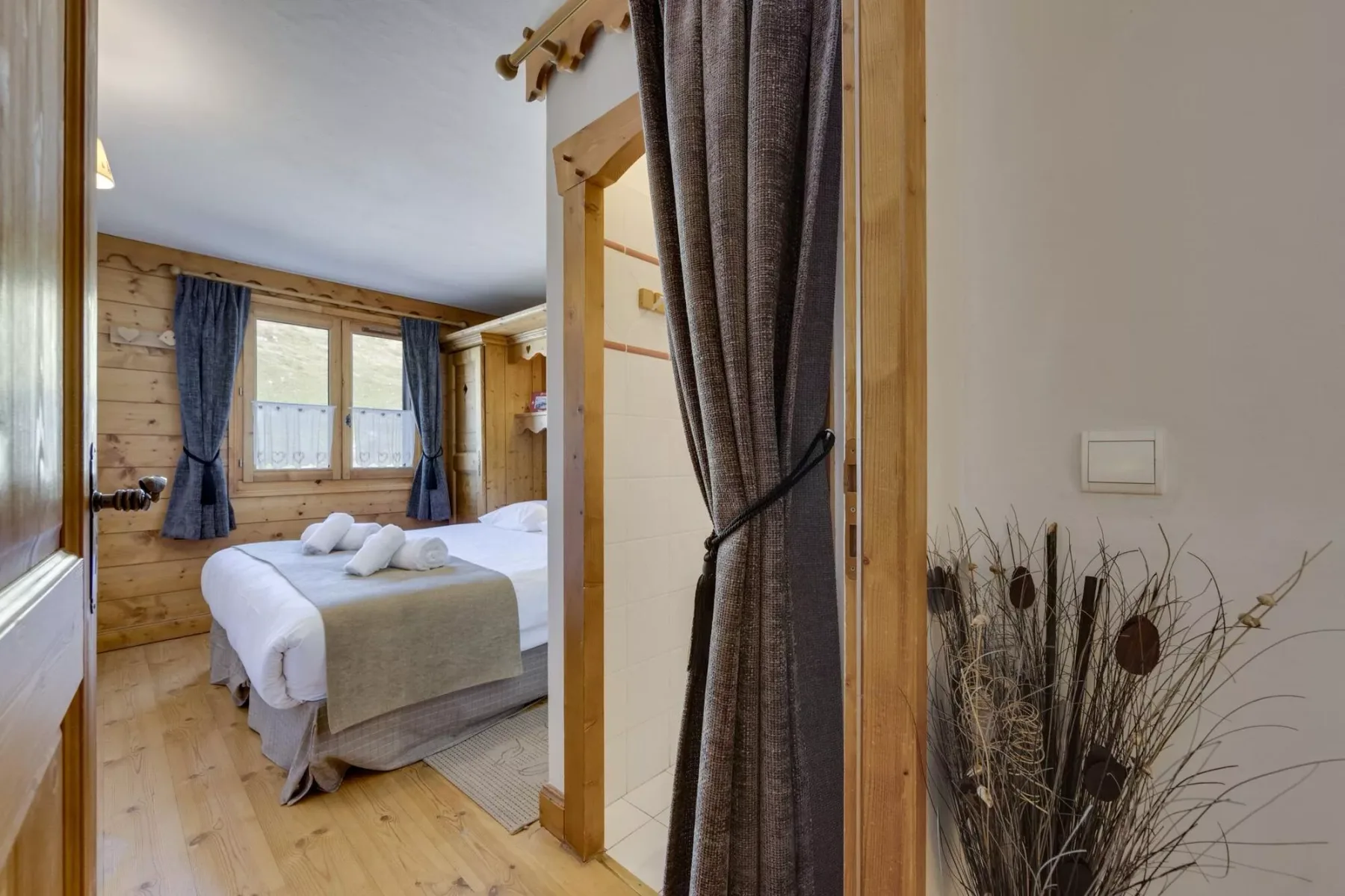 A bedroom with a bed beside a window, viewed through an open doorway.