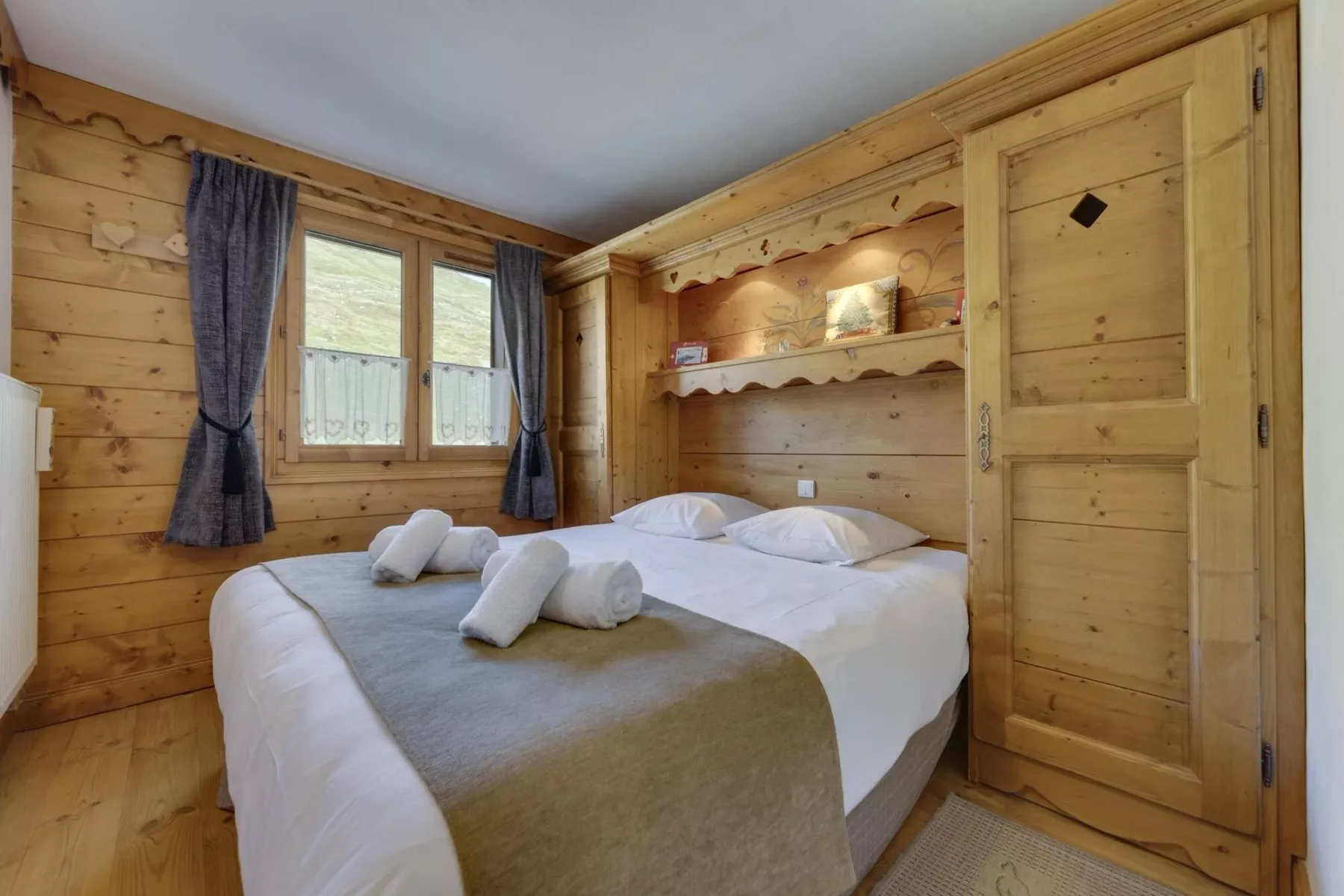 A bedroom with a bed dressed in white linens and a wood-paneled interior.