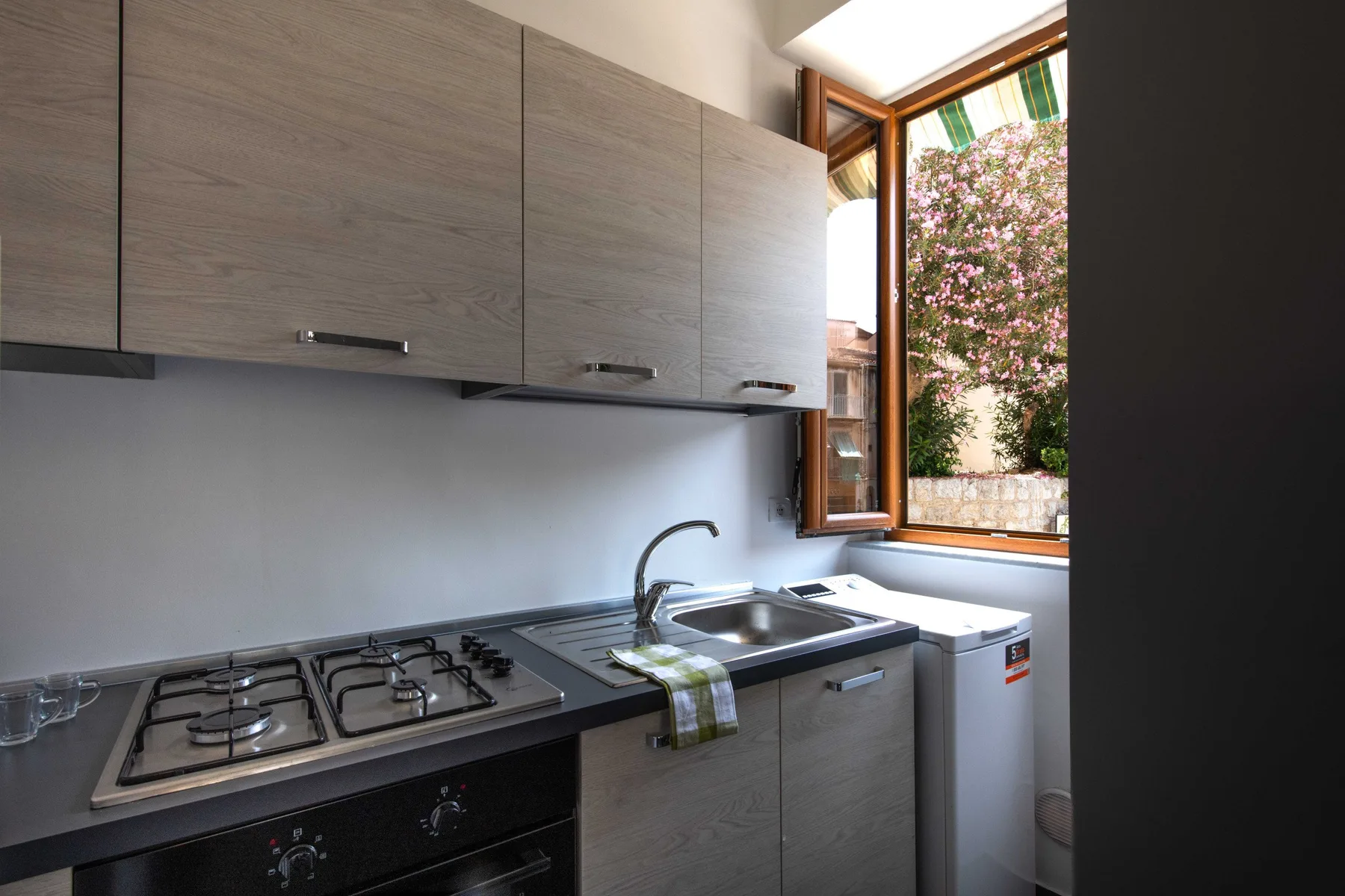 A compact kitchen with a gas cooktop, sink, and open window.