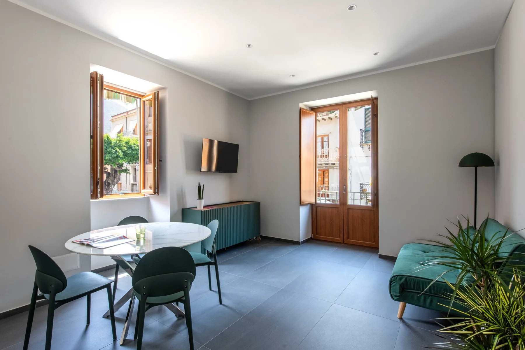 A bright dining and sitting room with a round table and tall windows.