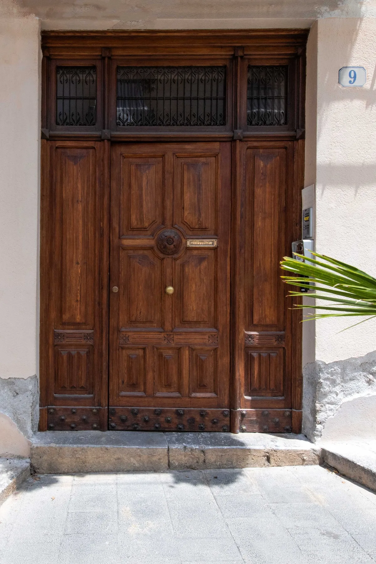 A carved wooden entrance door set into a pale exterior wall.
