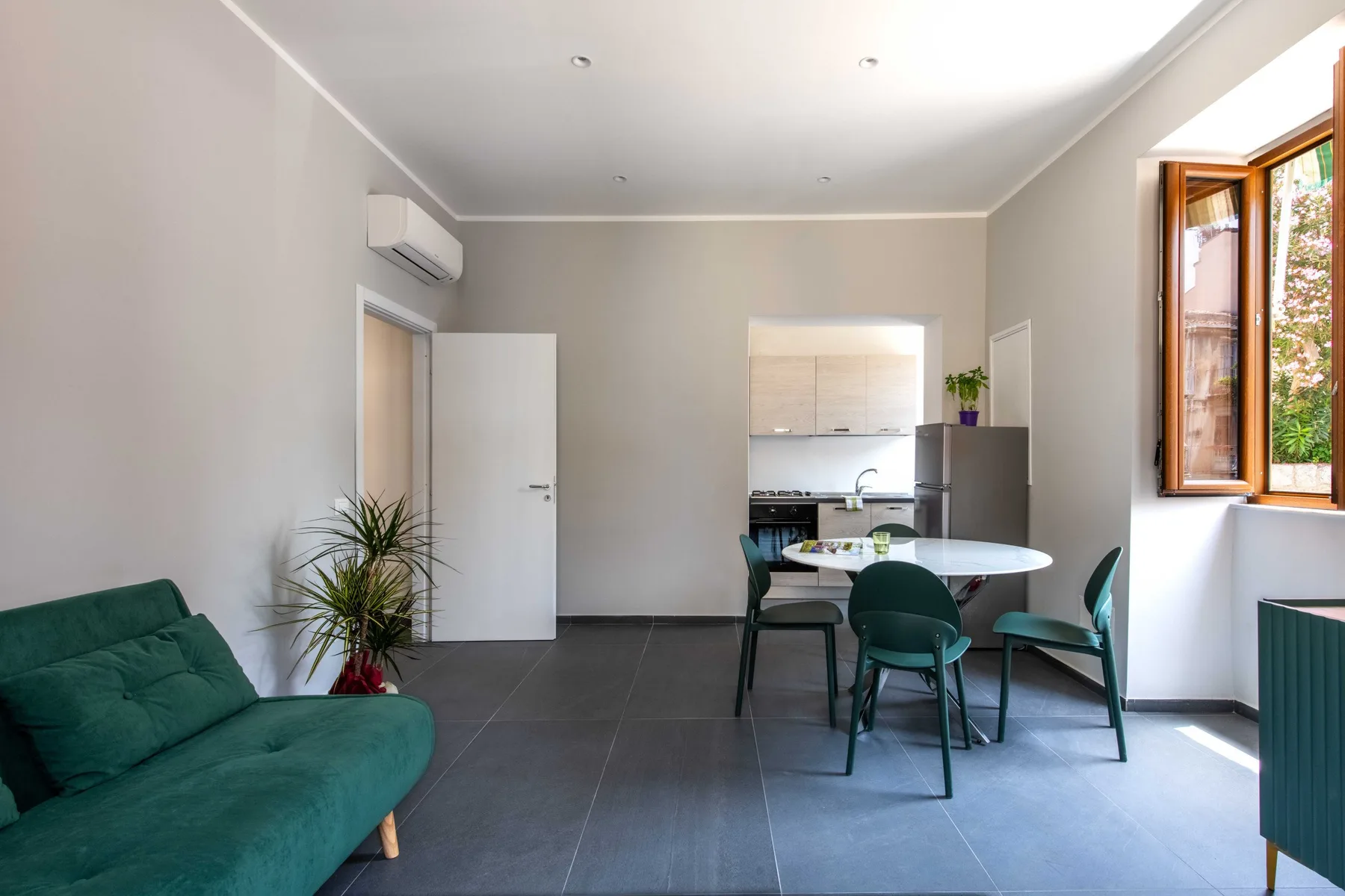 A bright open-plan living and dining area with a green sofa and table.
