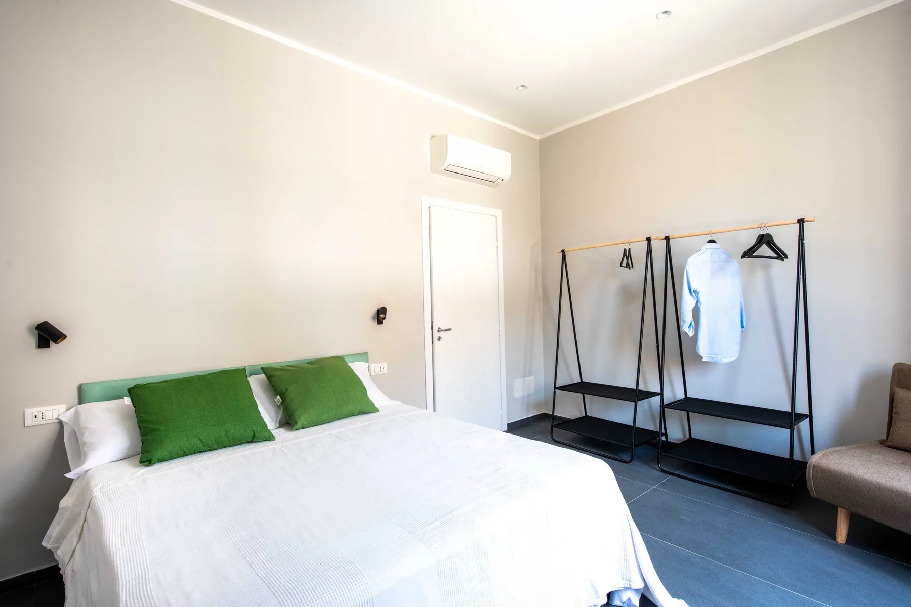 Bedroom with a bed, green pillows, and a freestanding clothes rack.