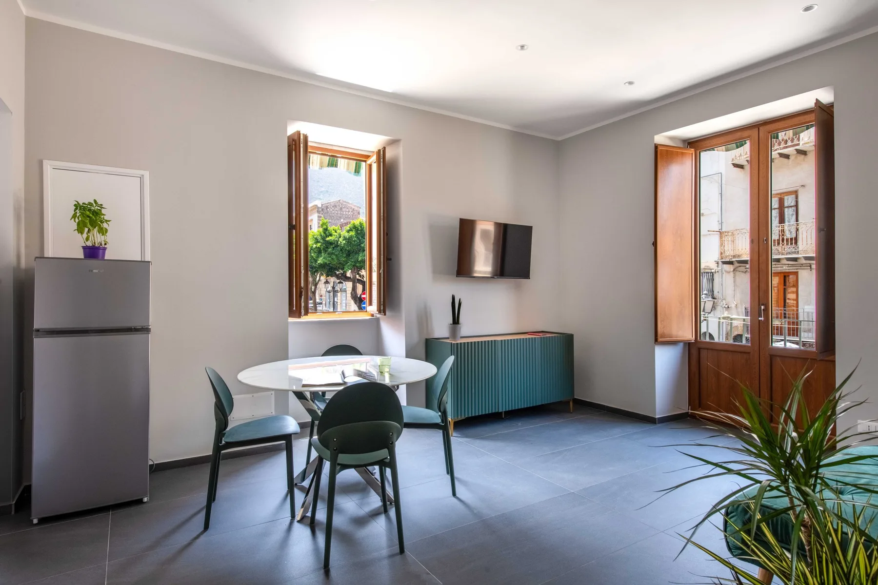 A bright dining area with a round table, seating, and tall windows.